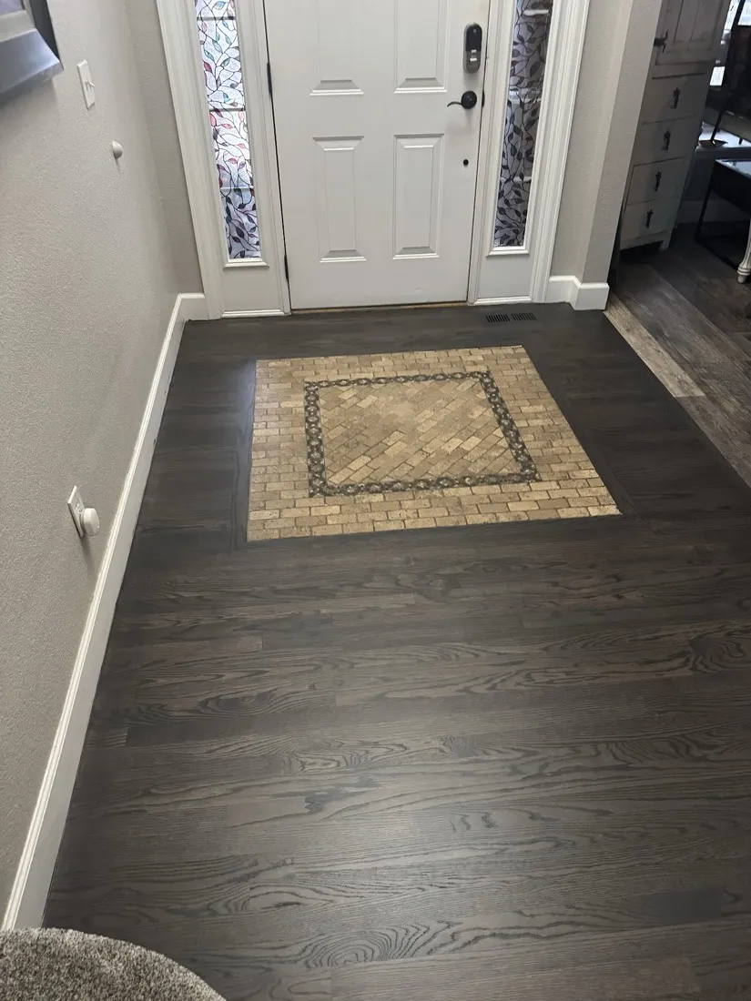Dark stained floor with a patterned inlay panel set into the entry