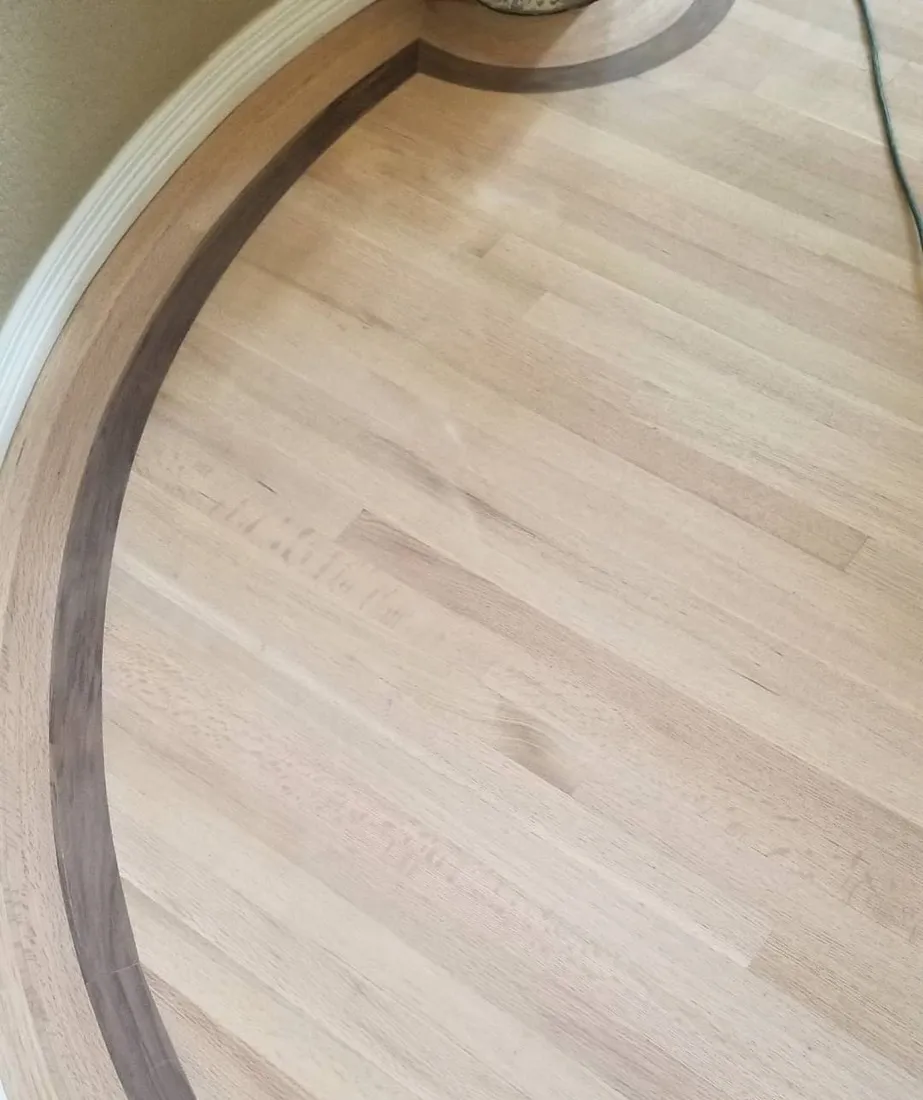 Curved border inlay sweeping through a wide plank oak floor