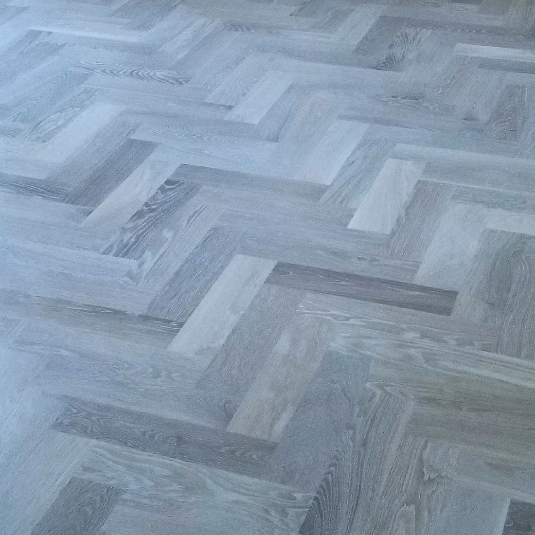 Gray-toned herringbone floor laid tight through a hallway