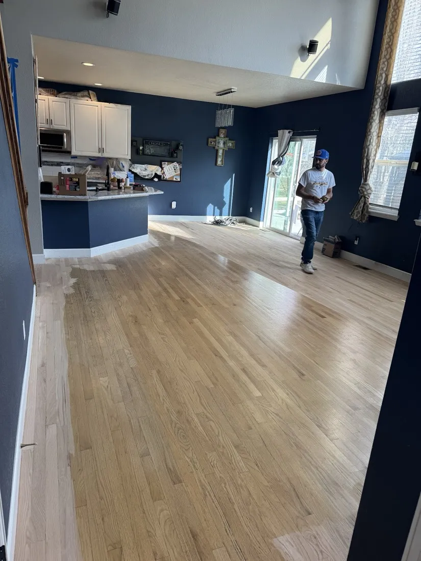 Freshly finished oak floor running into a kitchen with navy cabinets