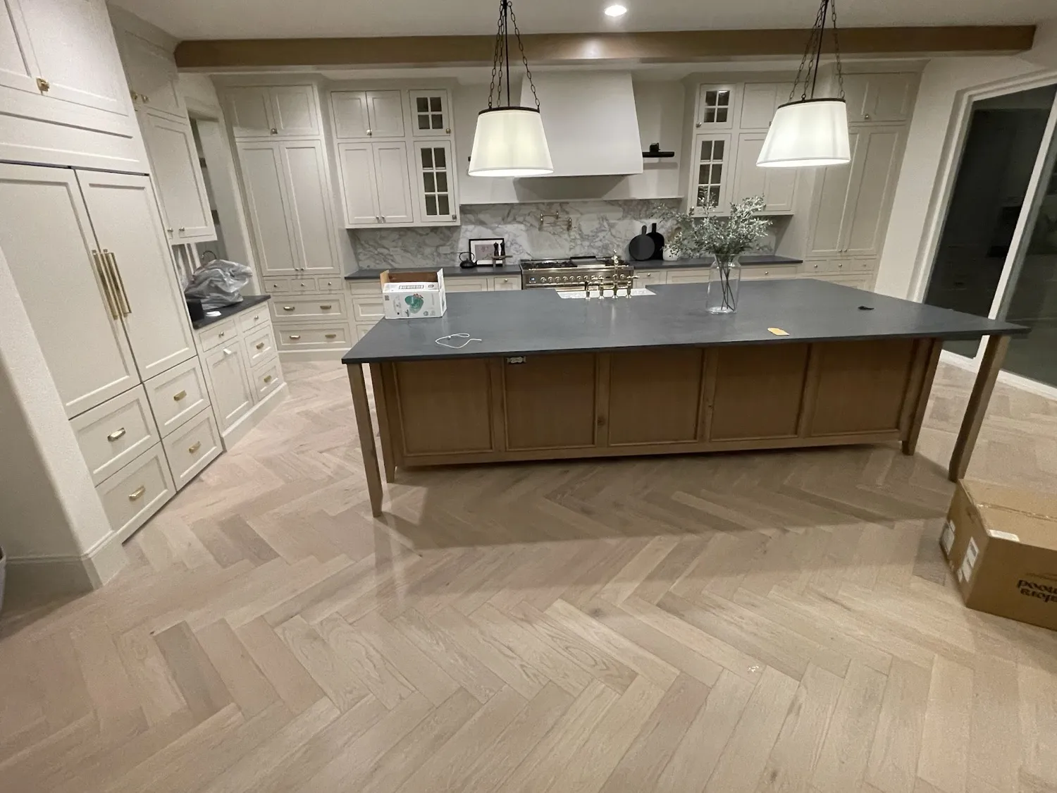 White oak herringbone floor installed through a large white kitchen